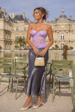 Bustier corset dentelle lilas fleuri 3D porté au Jardin du Luxembourg à Paris devant les chaises vert sauge et le Sénat, modèle femme 40 ans avec jupe satin gris anthracite