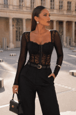 Bustier structuré noir à manches longues en dentelle porté avec pantalon tailleur noir au Palais Royal à Paris devant les colonnes de Buren