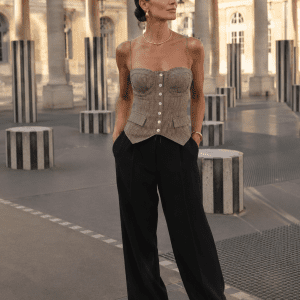 Bustier corset beige et marron pied-de-poule porté avec un pantalon tailleur noir fluide au Palais Royal devant les colonnes de Buren, style mode éditorial chic et sophistiqué.