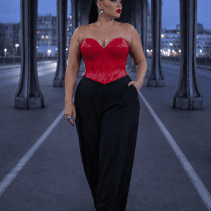 Femme élégante de 45 ans portant un bustier corset gothique rouge effet latex avec un pantalon tailleur noir large et des escarpins noirs au Pont Bir-Hakeim à Paris pendant la blue hour
