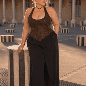 Femme grande taille 3XL portant un bustier corset marron steampunk avec pantalon noir large au Palais Royal près des Colonnes de Buren dans une ambiance éditoriale haute couture.