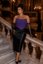 Femme élégante de 45 ans portant un bustier violet à paillettes scintillantes avec jupe satin noire au Palais Garnier dans le grand escalier de marbre