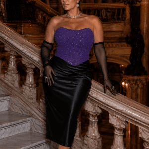 Femme élégante de 45 ans portant un bustier violet à paillettes scintillantes avec jupe satin noire au Palais Garnier dans le grand escalier de marbre