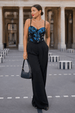 Bustier corseté noir brodé bleu et turquoise porté avec pantalon tailleur large noir au Palais Royal à Paris