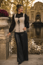 Femme élégante de 45 ans portant un corset bustier blanc cassé style pirate renaissance avec blouse noire en dentelle et pantalon palazzo noir au Jardin du Luxembourg à Paris