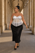Femme élégante portant un corset bustier blanc transparent grande taille avec jupe satinée noire au Palais Royal à Paris
