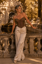 Femme élégante de plus de 40 ans portant un corset bustier marron café coupe cœur avec pantalon satin crème au Jardin du Luxembourg à Paris devant la Fontaine Médicis