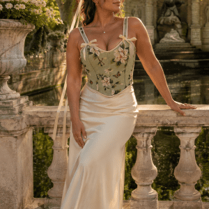 Femme élégante de 45 ans portant un corset bustier fleuri vert sauge avec jupe longue satin crème au bord de la Fontaine Médicis au Jardin du Luxembourg