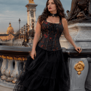 Femme de 40 ans portant un corset gothique noir et rouge à bretelles avec une longue jupe en tulle noire au Pont Alexandre III à Paris lors d’une séance photo éditoriale de mode