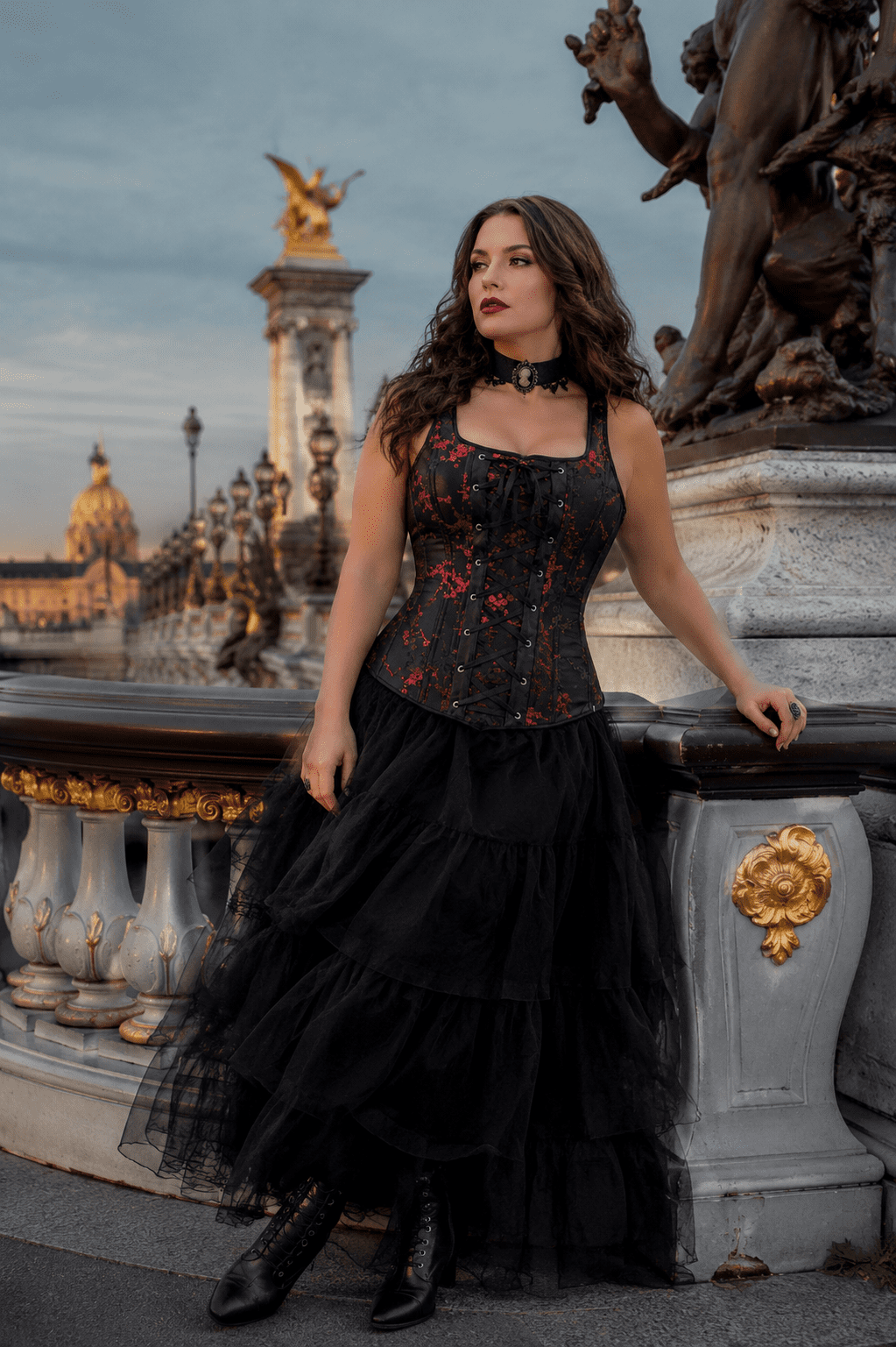 Femme de 40 ans portant un corset gothique noir et rouge à bretelles avec une longue jupe en tulle noire au Pont Alexandre III à Paris lors d’une séance photo éditoriale de mode