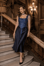 modèle femme 40 ans portant un corset jean bleu fleuri vintage à bretelles style renaissance avec jupe satin bleu nuit au Palais Garnier