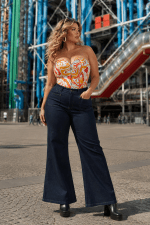 Femme portant un corset multicolore psychédélique grande taille avec pantalon pattes d’éléphant en denim brut devant le Centre Pompidou à Paris dans une ambiance mode éditoriale rétro moderne.