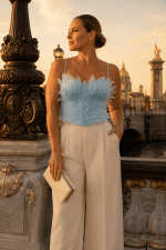 Femme portant un corset soutien-gorge bleu ciel à plumes avec pantalon crème élégant au Pont Alexandre III à Paris