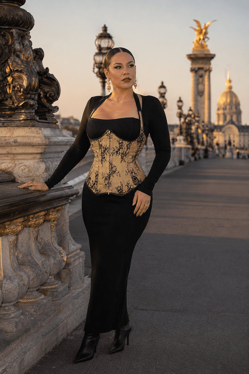 Mannequin femme taille L portant un corset steampunk doré fleuri noir à licou avec une robe noire longue ajustée au pont Alexandre III à Paris.