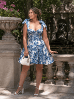 Femme portant une robe bustier bleue et blanche à imprimé floral avec jupe plissée évasée au jardin du Luxembourg près de la fontaine Médicis.