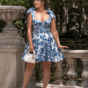 Femme portant une robe bustier bleue et blanche à imprimé floral avec jupe plissée évasée au jardin du Luxembourg près de la fontaine Médicis.