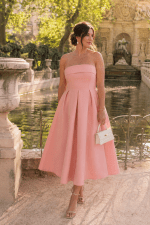 Femme portant une robe bustier midi rose trapèze effet corset devant la Fontaine Médicis au Jardin du Luxembourg à Paris