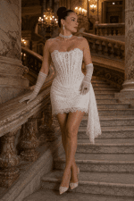 Robe corset mini en dentelle florale blanche portée au Palais Garnier sur un escalier en marbre avec gants en tulle et escarpins nude