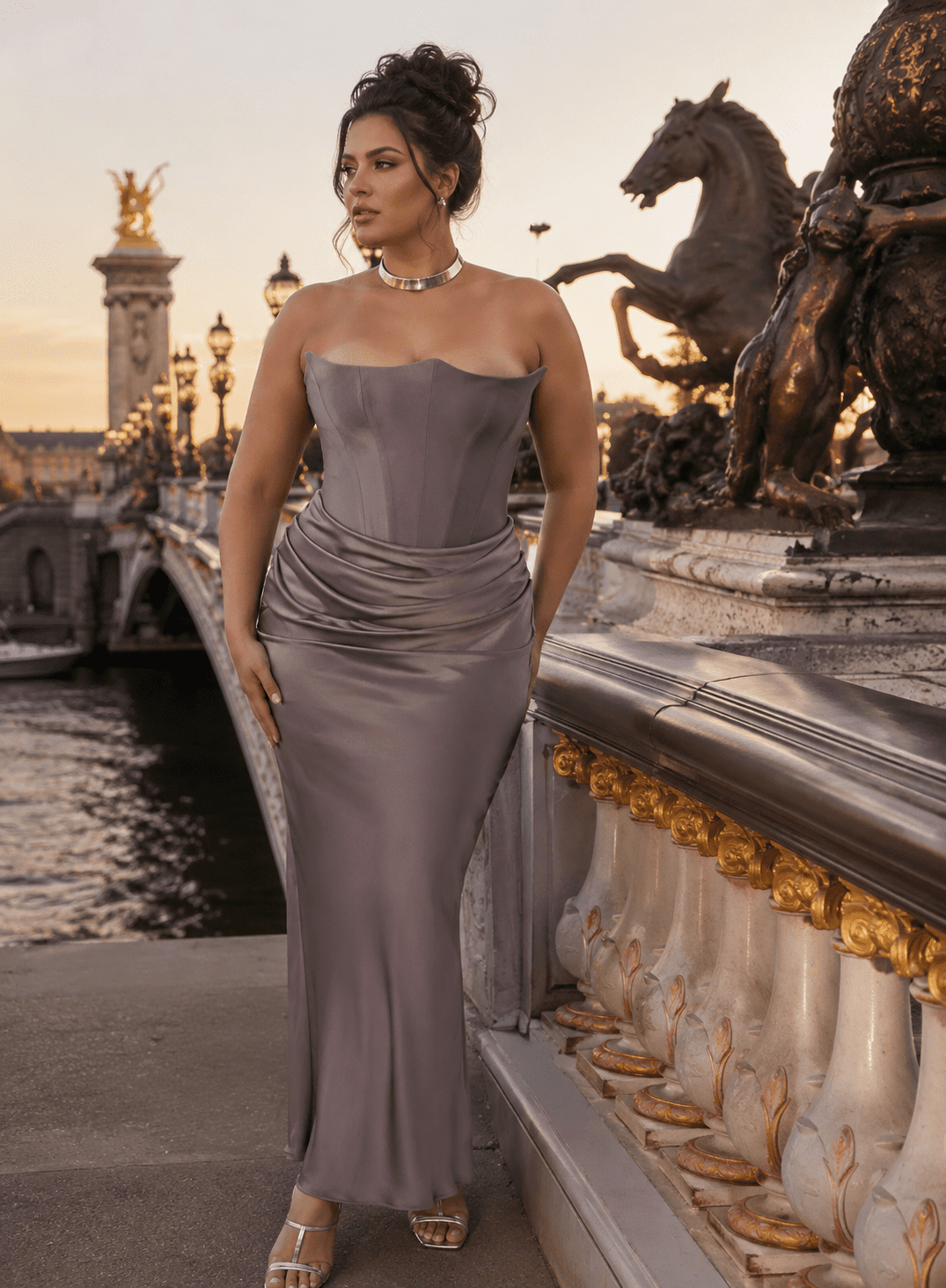 Femme élégante portant une robe longue grise satinée drapée style corset au Pont Alexandre III à Paris pendant la golden hour avec détails dorés et ambiance éditoriale luxe.