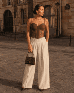 Femme de 40 ans portant un corset bustier marron en dentelle florale avec pantalon tailleur crème à Place Dauphine au coucher du soleil.