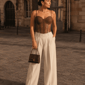 Femme de 40 ans portant un corset bustier marron en dentelle florale avec pantalon tailleur crème à Place Dauphine au coucher du soleil.