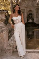 Femme de 40 ans portant un corset bustier blanc long transparent avec pantalon de tailleur ivoire à pinces à la fontaine de Médicis à Paris.
