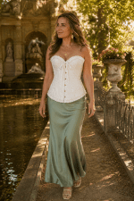 Corset bustier blanc style vintage à motifs baroques ton sur ton porté avec une jupe longue vert sauge fluide à la fontaine Médicis à Paris