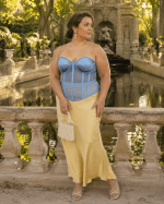 Femme de 40 ans portant un corset bustier bleu transparent grande taille avec une jupe maxi satin jaune beurre à la fontaine de Médicis au Jardin du Luxembourg.