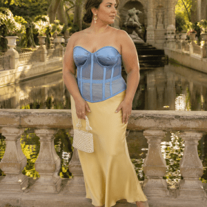 Femme de 40 ans portant un corset bustier bleu transparent grande taille avec une jupe maxi satin jaune beurre à la fontaine de Médicis au Jardin du Luxembourg.
