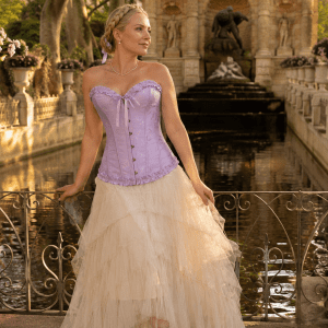 Femme de 40 ans portant un corset bustier lilas victorien romantique avec jupe longue en tulle crème à la fontaine de Médicis au Jardin du Luxembourg, photo éditoriale haute couture à la golden hour du matin.