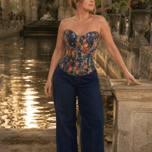 Femme de 40 ans portant un corset bustier bleu style jean à imprimé floral vintage avec un jean large taille haute indigo foncé à la Fontaine de Médicis au Jardin du Luxembourg à Paris, lumière golden hour du matin.