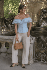 femme élégante de 40 ans portant un corset bustier victorien bleu ciel à volants en voile et motifs floraux jacquard, photographiée à la fontaine de Médicis au jardin du Luxembourg à Paris