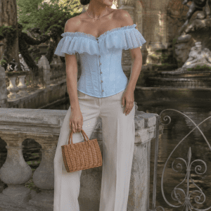 femme élégante de 40 ans portant un corset bustier victorien bleu ciel à volants en voile et motifs floraux jacquard, photographiée à la fontaine de Médicis au jardin du Luxembourg à Paris