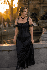 Corset victorien romantique noir et blanc porté à la Fontaine Médicis à Paris, avec manches bouffantes en tulle blanc à pois, dentelle noire, jupe longue en satin noir et bottines victoriennes, photographié à la golden hour.