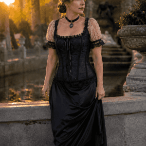Corset victorien romantique noir et blanc porté à la Fontaine Médicis à Paris, avec manches bouffantes en tulle blanc à pois, dentelle noire, jupe longue en satin noir et bottines victoriennes, photographié à la golden hour.
