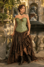 Photo éditoriale de mode d'un corset bustier vintage vert sauge pastel en brocart floral ton sur ton, porté avec une jupe longue asymétrique marron chocolat à la fontaine Médicis à Paris.