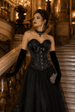 Corset néo-victorien noir bustier vintage en brocart baroque ton sur ton porté avec une longue jupe en tulle noir sur le grand escalier du Palais Garnier à Paris.