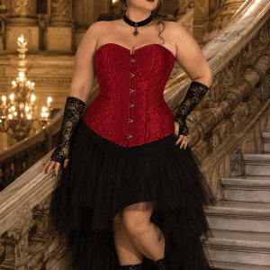 Femme grande taille portant un corset gothique rouge brocart au Palais Garnier, avec jupe asymétrique en tulle noir et bottines victoriennes.