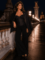 Femme de 40 ans portant un corset soutien-gorge noir brillant avec un blazer noir oversize posé sur les épaules et un pantalon palazzo noir au Pont Alexandre III.