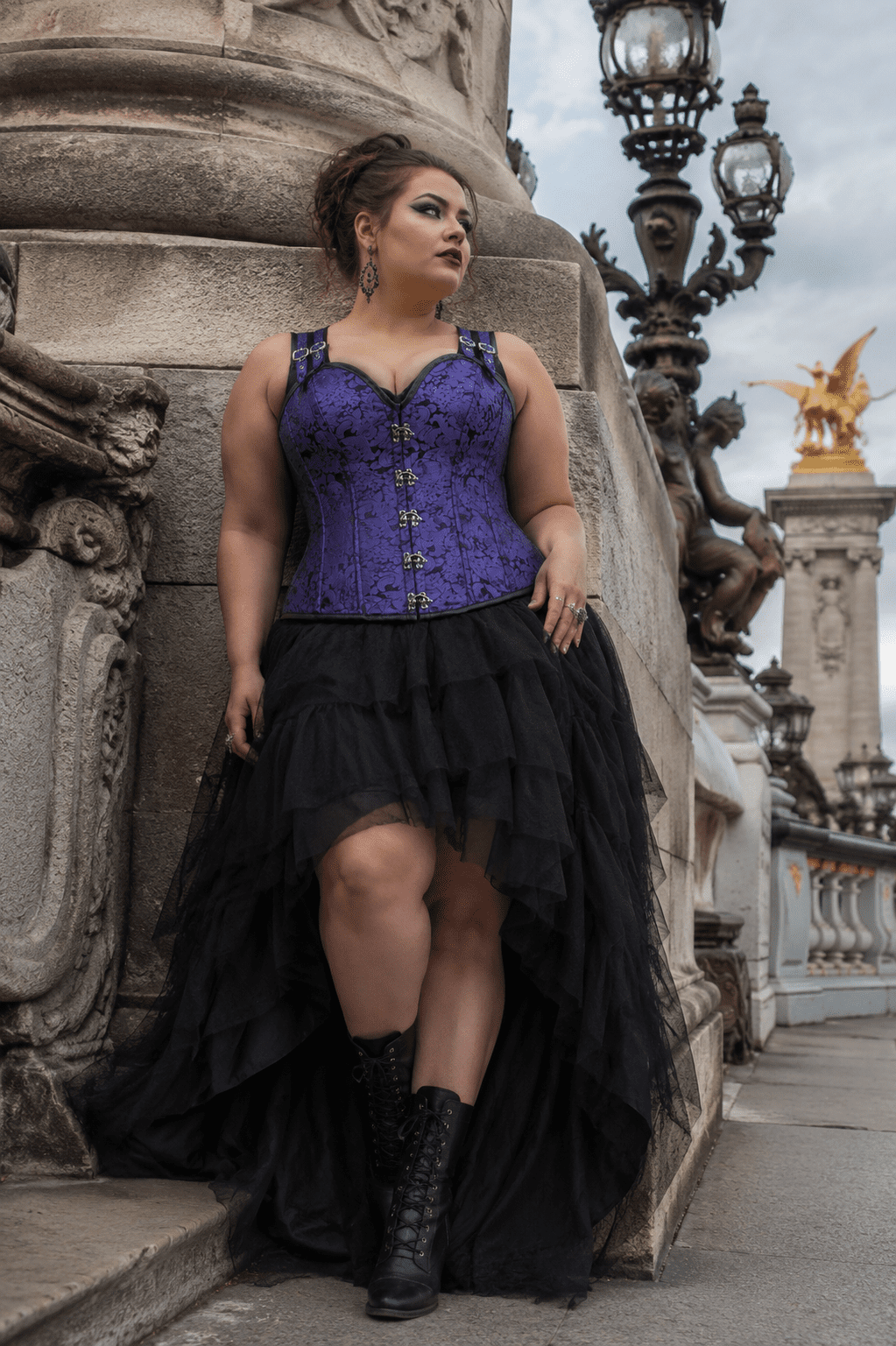 corset steampunk violet en brocart jacquard à motifs baroques avec dos haut, fermeture à crochets métalliques sur le devant et bretelles réglables, porté avec une jupe asymétrique en tulle noir au pont Alexandre III à Paris