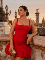 Femme de 40 ans portant une robe bustier courte rouge écarlate à volants, photographiée au Pont Alexandre III à Paris à la golden hour, avec détails dorés du pont en arrière-plan.