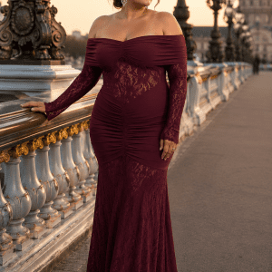 Femme de 45 ans portant une robe longue de soirée sirène bordeaux avec épaules dénudées, manches longues en dentelle florale et coupe élégante au Pont Alexandre III à Paris.