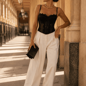 Femme de 40 ans portant un bustier corset noir à dentelle transparente avec pantalon palazzo blanc cassé galerie montpensier au palais royal à Paris.