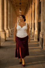 Femme taille 3XL portant un corset bustier blanc en brocart satiné avec jupe midi bordeaux au Palais royal galerie valois à Paris
