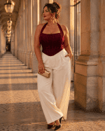 Corset bustier dos nu licou bordeaux porté avec un pantalon de tailleur crème a la galerie montpensier a Paris au coucher du soleil.