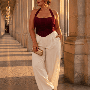 Corset bustier dos nu licou bordeaux porté avec un pantalon de tailleur crème a la galerie montpensier a Paris au coucher du soleil.