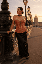 Corset bustier gothique orange brûlé et doré porté avec une longue jupe noire en satin au pont Alexandre III à Paris pendant la golden hour du soir.