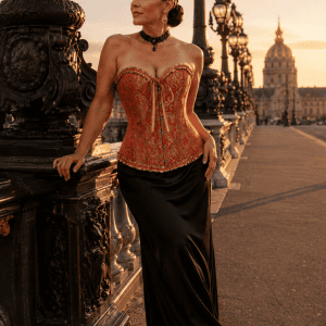 Corset bustier gothique orange brûlé et doré porté avec une longue jupe noire en satin au pont Alexandre III à Paris pendant la golden hour du soir.