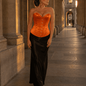 Femme de 45 ans portant un corset bustier satin orange brûlé avec jupe maxi noire à la galerie de montpensier au palais royal a paris au coucher du soleil.