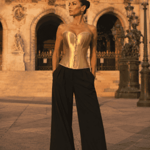 Corset bustier steampunk doré métallique porté avec un pantalon palazzo noir sur le parvis du palais garnier à Paris au coucher du soleil.